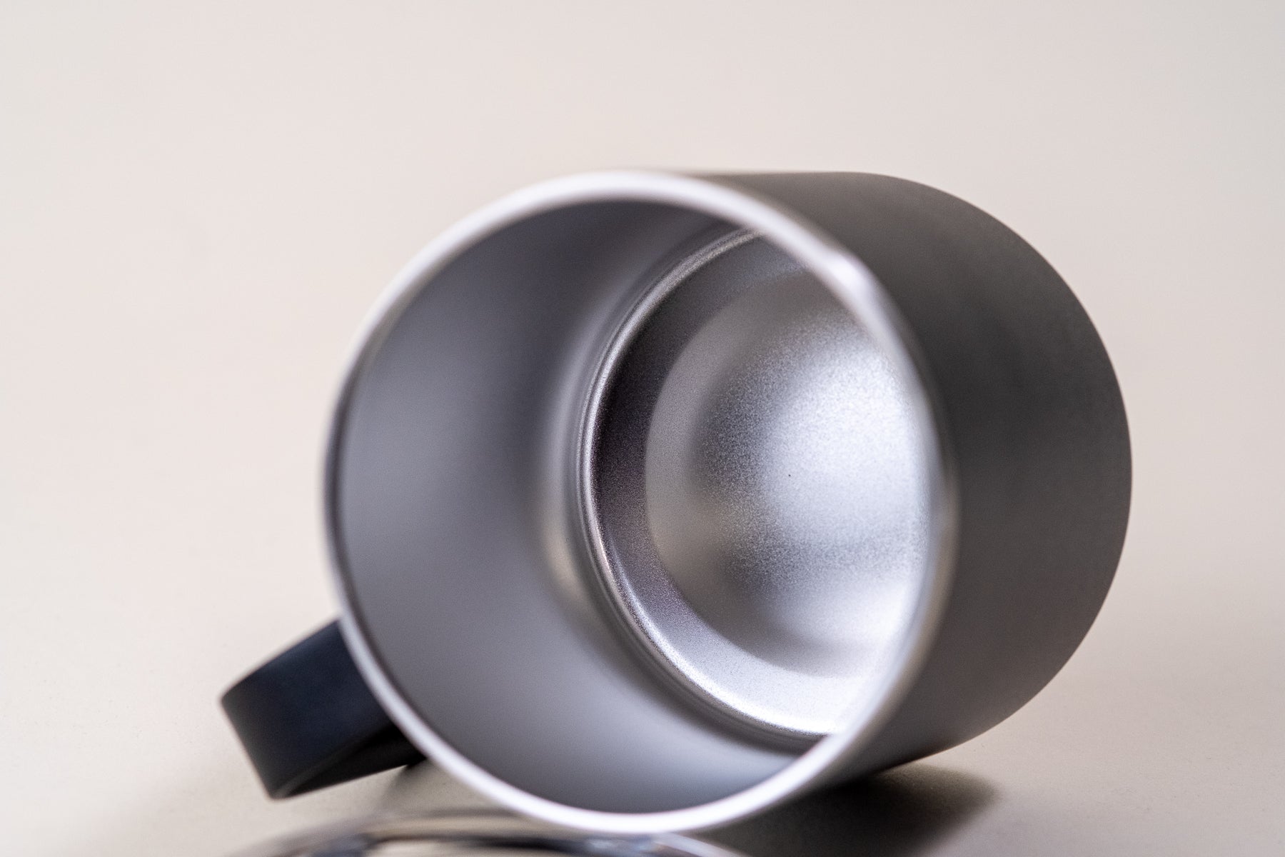 Close-up view of the interior of a black insulated coffee mug, showing its stainless steel double-wall vacuum construction for temperature retention.