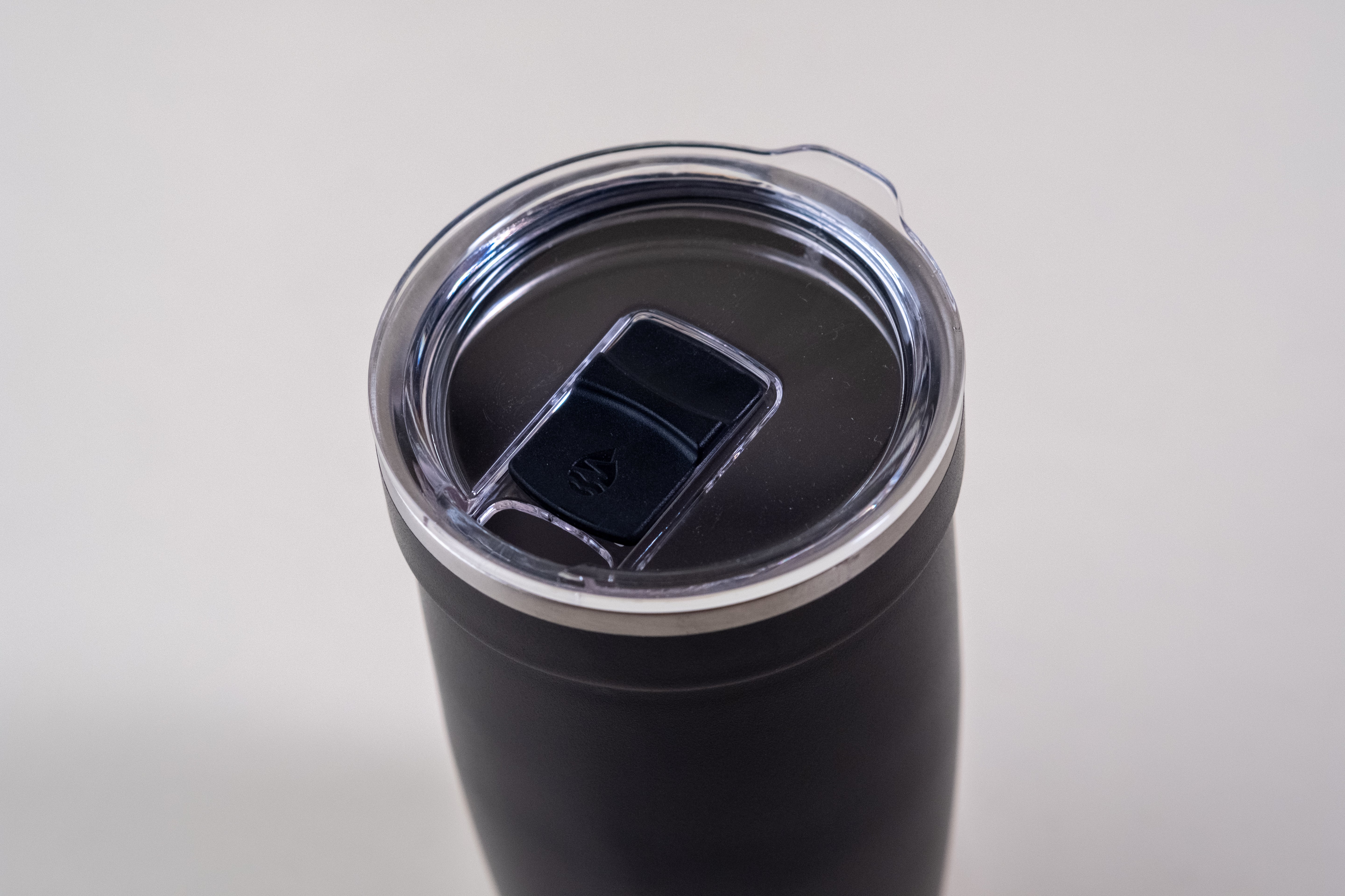 Black insulated travel tumbler with a secure, spill-resistant lid featuring a sliding closure.