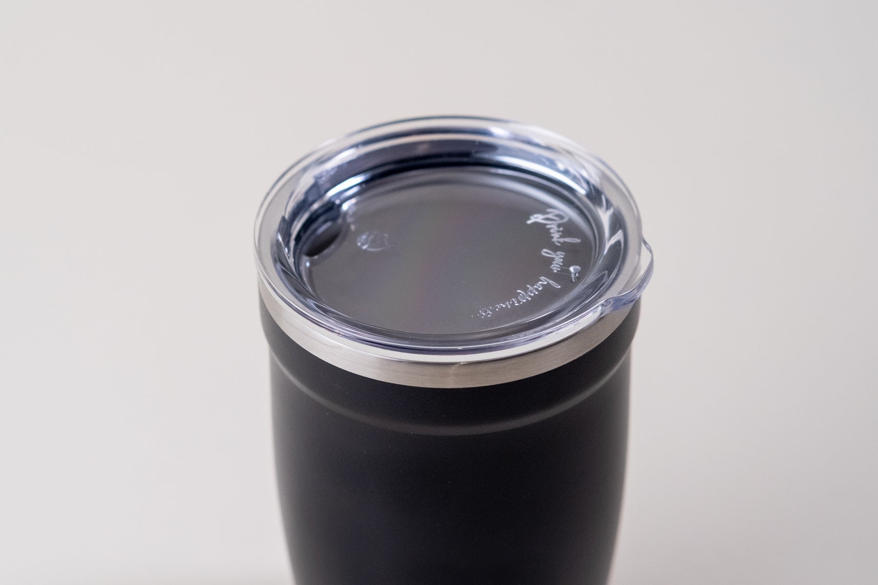 Black insulated tumbler with a clear spill-resistant lid featuring an engraved quote. Stainless steel travel mug designed for keeping beverages hot or cold.