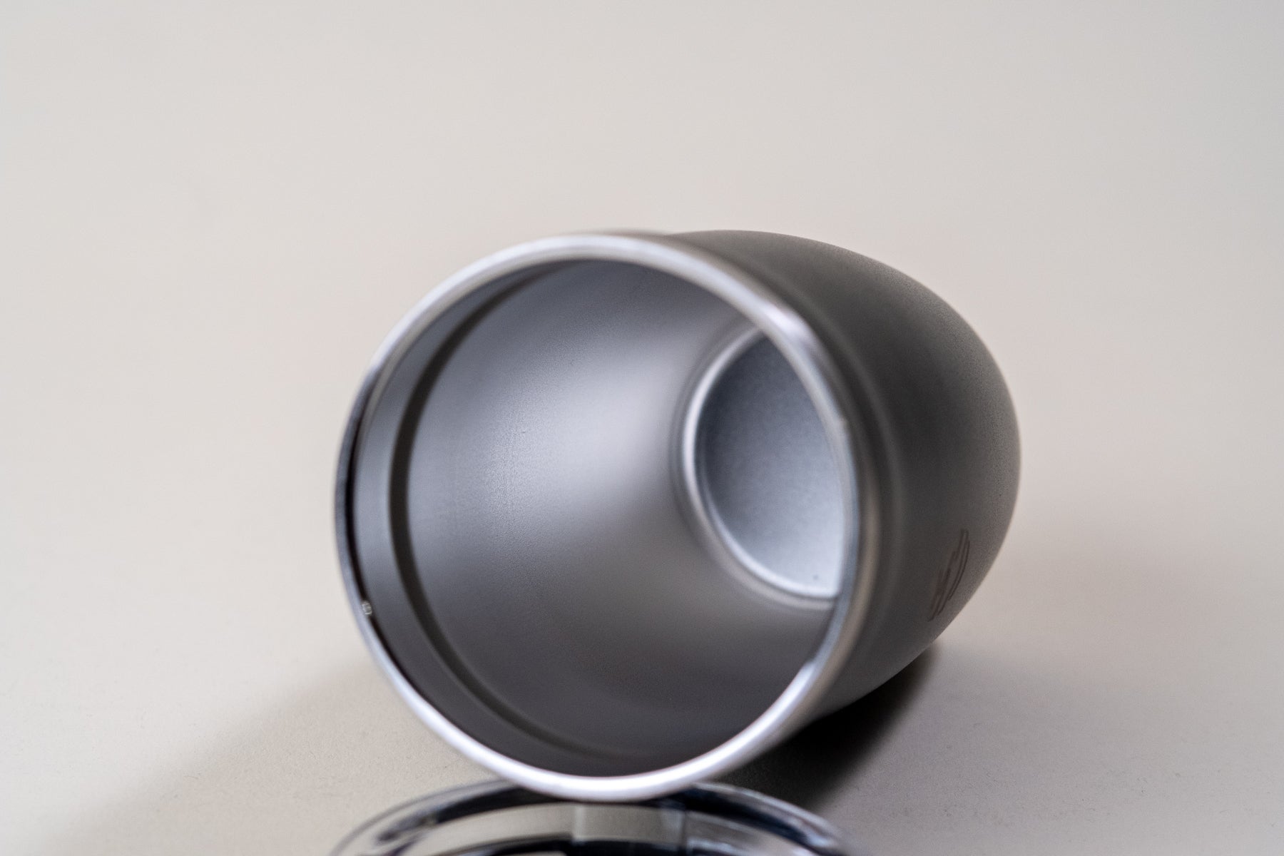 Close-up of the interior of a black insulated tumbler with a stainless steel finish and a double-wall vacuum design. Removable clear spill-resistant lid shown beside it.