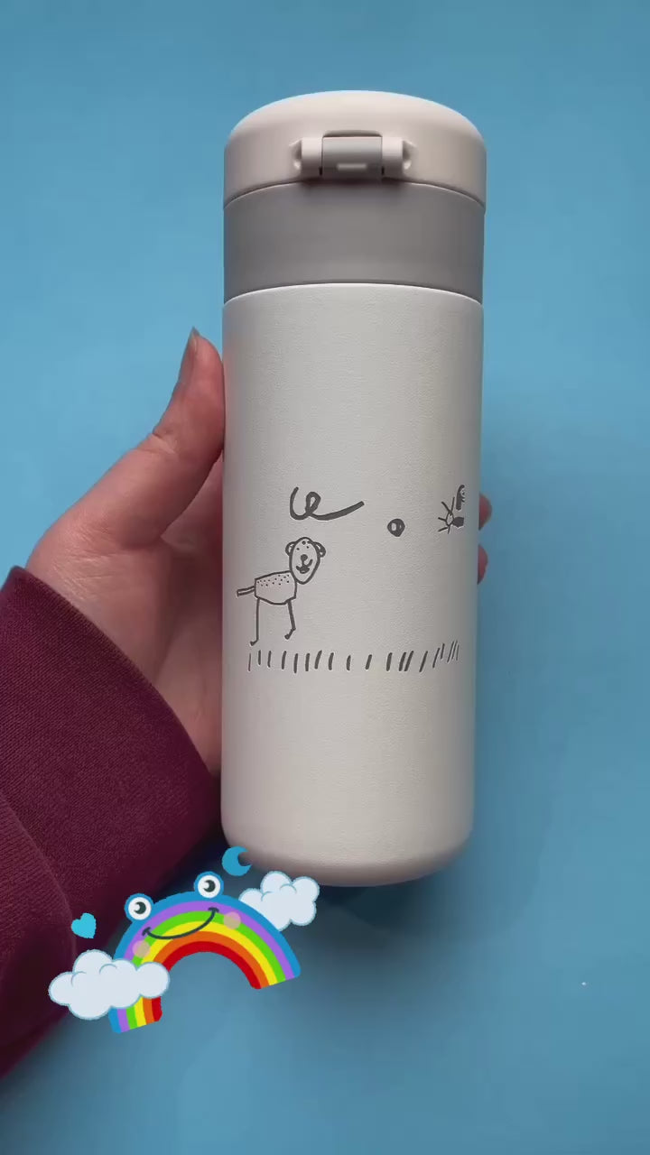 Load video: Custom white insulated tumbler with a child’s hand-drawn illustration, featuring a lion and a bee, on a blue background. Personalized travel mug with unique artwork.