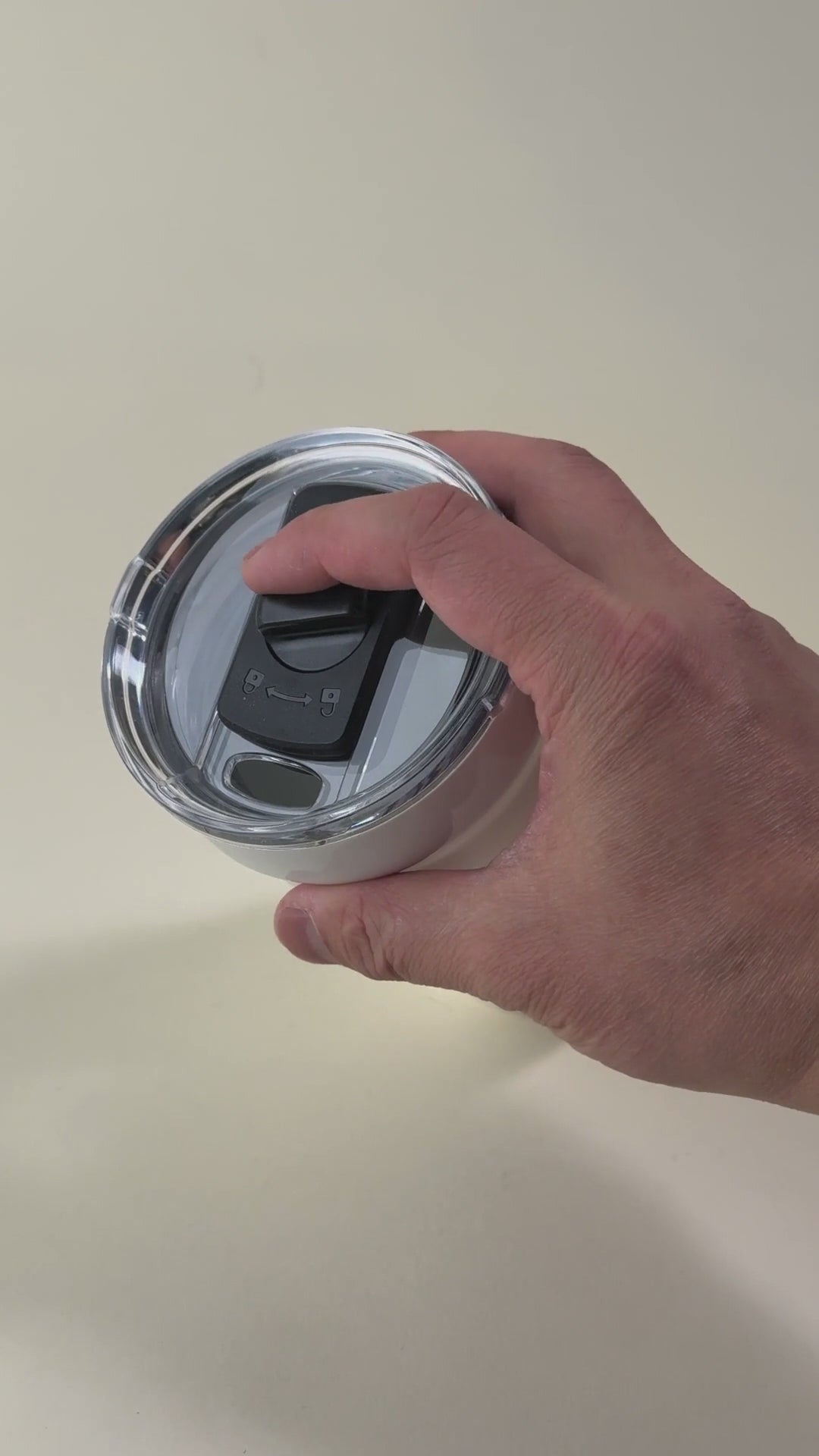 Load video: Hand pressing the sliding lock on a white insulated tumbler with a spill-resistant lid. Stainless steel travel mug designed for secure and convenient drinking.