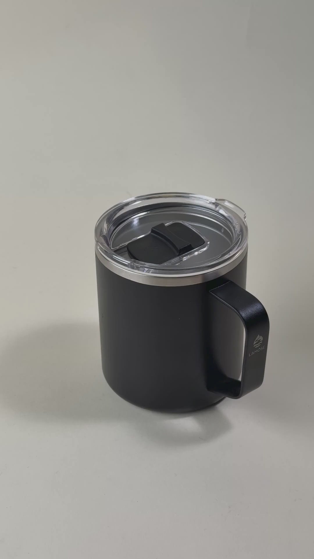 Load video: Black insulated coffee mug with a clear spill-resistant lid and sturdy handle. Stainless steel design, perfect for keeping beverages hot or cold for extended hours.