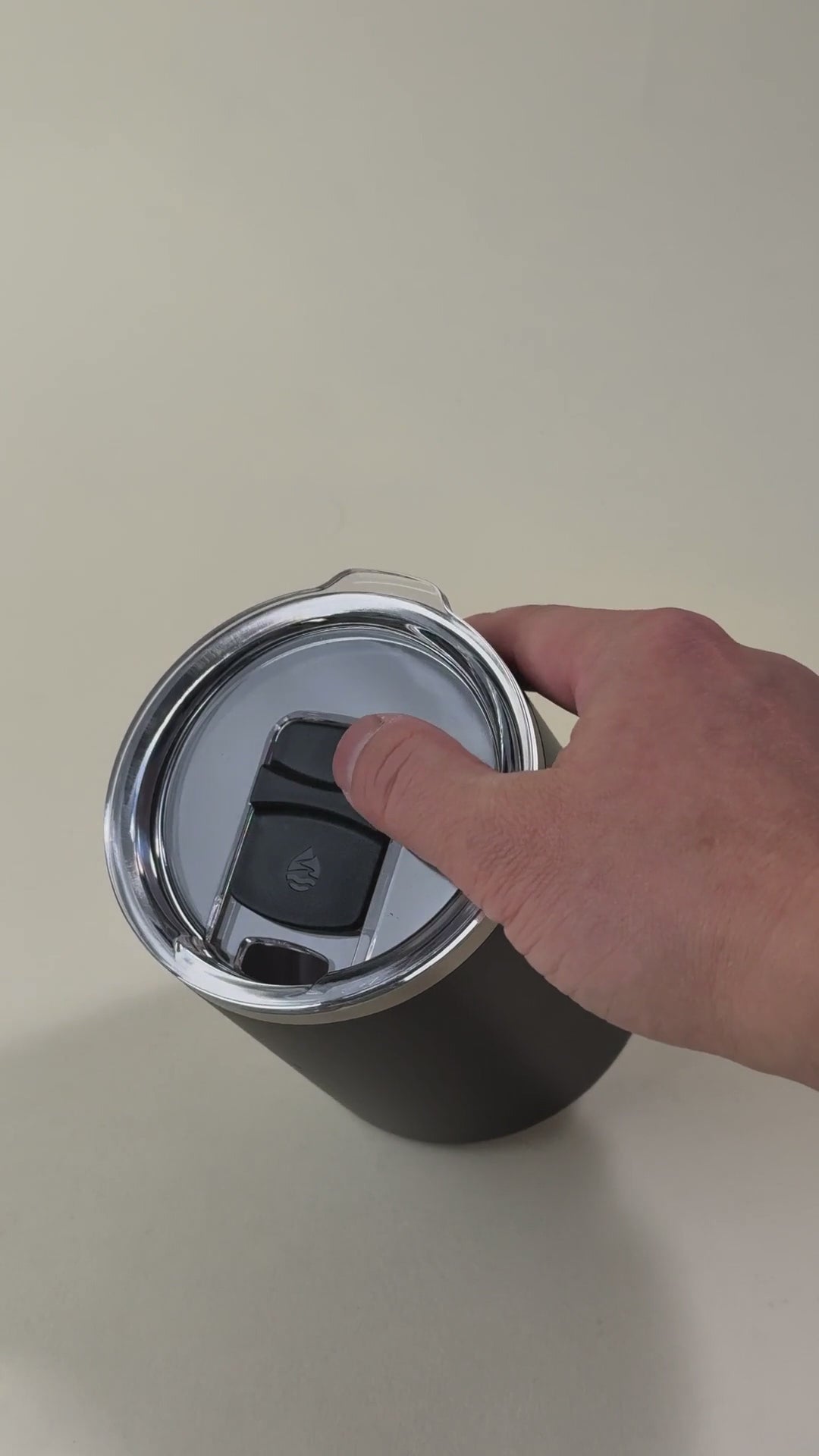 Load video: Hand opening the sliding lid of a black insulated coffee mug. Stainless steel mug with a spill-resistant clear lid, designed for hot and cold beverages.