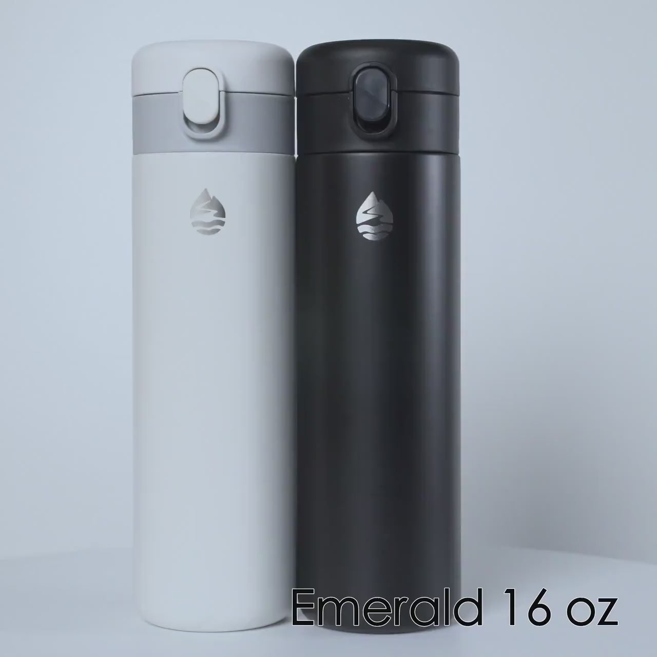 Load video: Emerald 16 oz insulated stainless steel travel tumblers in sleek black and white colors, featuring a secure flip-top lid and minimalist design.