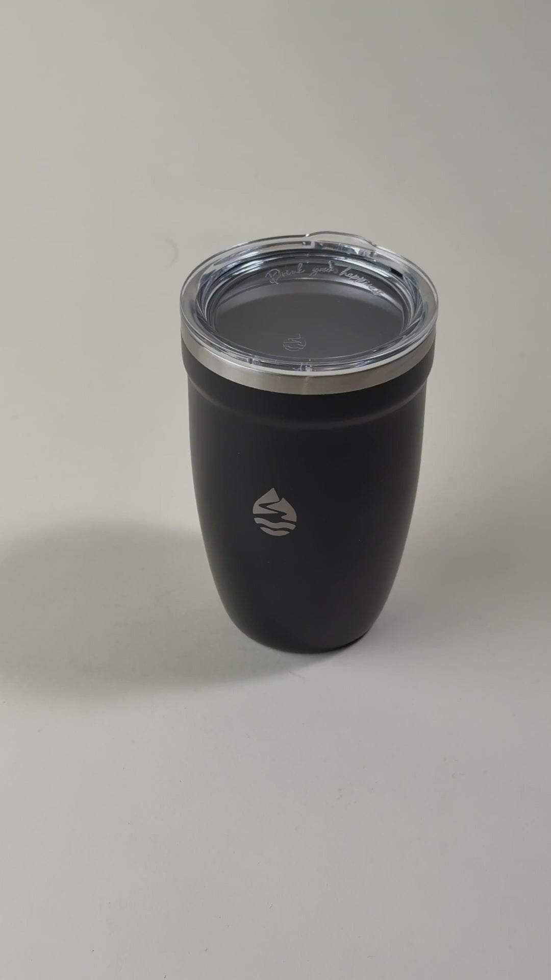 Load video: Hand holding a black insulated tumbler with a clear spill-resistant lid. Stainless steel travel mug designed to keep beverages hot or cold for extended hours.