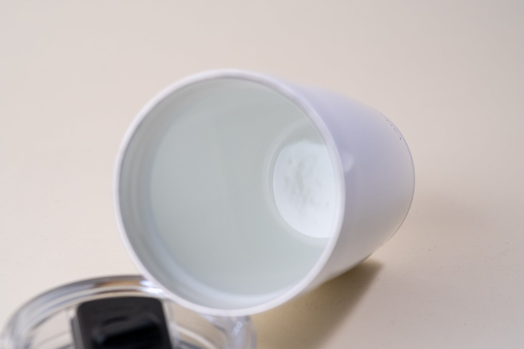 Close-up view of the interior of a white enamel-coated insulated tumbler, showing its smooth finish and durable design for hot and cold beverages.