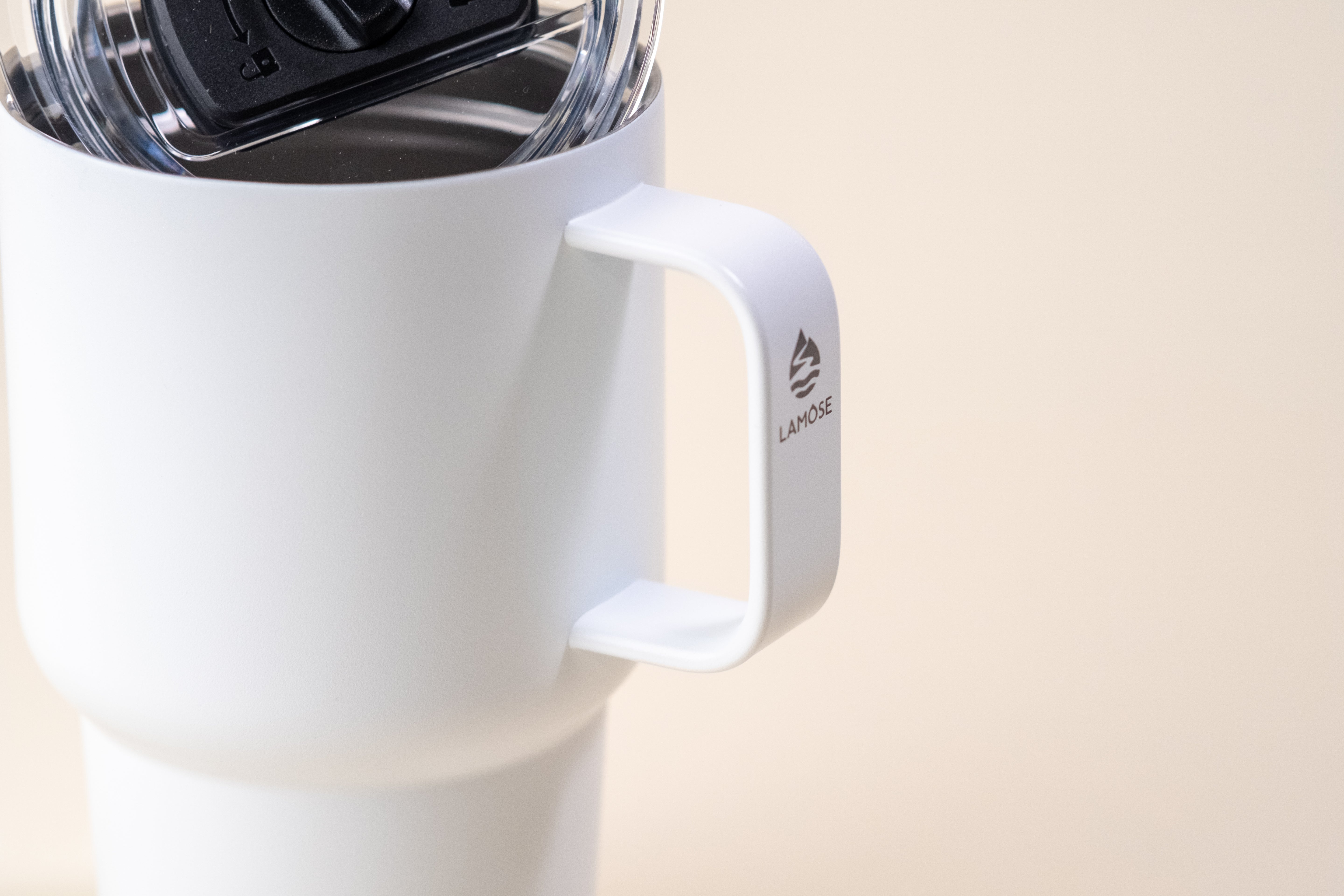 Close-up of a white insulated mug with a sturdy handle and a spill-proof lid, featuring the Lamose logo.